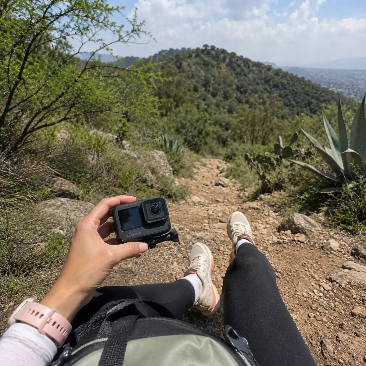 Woman holding an action camera while hiking on a scenic mountain trail