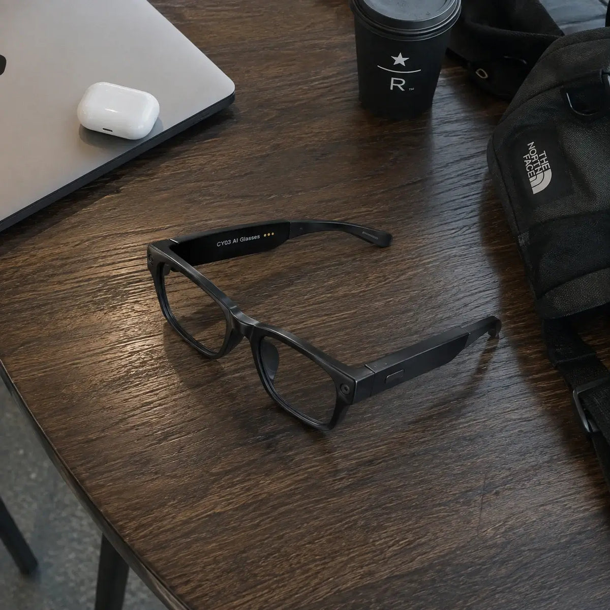 CY03 AI smart glasses on a table with everyday travel essentials